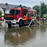 Einsatzkräfte der Feuerwehr Gerolzhofen pumpen am Sonntagvormittag Wasser von einer überfluteten Straßenkreuzung in Mering im Landkreis Aichach-Friedberg.