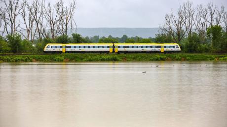 Ein Zug fährt an einer vom Regen überfluteten Wiese vorbei.