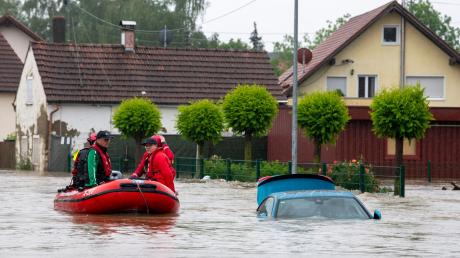 Die Wasserwacht fährt mit einem Schlauchboot durch eine überflutete Straße.