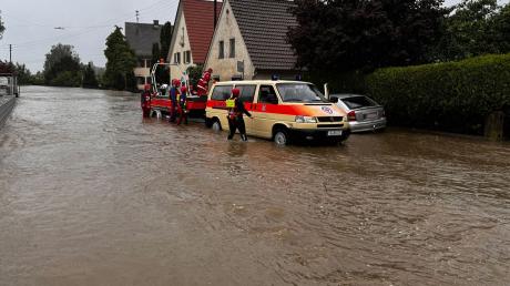 Die Wasserrettung ist in einer überschwemmten Straße in Diedorf im schwäbischen Landkreis Augsburg im Einsatz