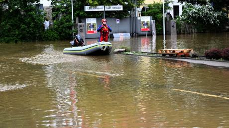 Ein Helfer kommt mit dem Schlauchboot zu einer überschwemmten Tankstelle in Allershausen.