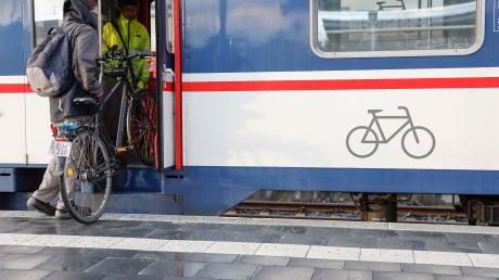 Ein Mann muss sein Fahrrad in den Zug heben.