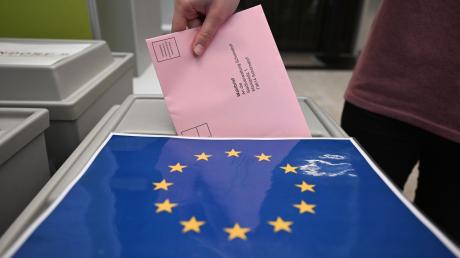 Ein Wahlbrief mit einem Stimmzettel für die Europawahl wird in einem Wahllokal für die Briefwahl in eine Wahlurne gesteckt.