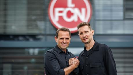Der neue FCN-Trainer Miroslav Klose (r) steht mit dem FCN-Sportvorstand Joti Chatzialexiou vor dem Vereins-Logo.