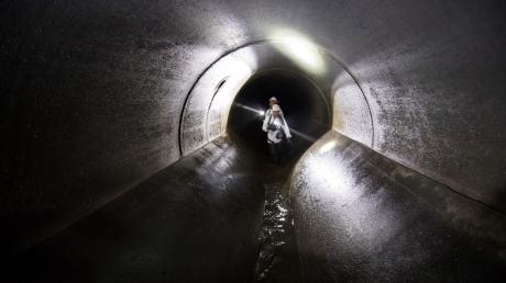 Kanalarbeiter begehen während eines Kontrollgangs die unterirdische Kanalisation.