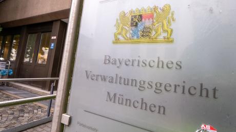 Ein Schild mit dem bayerischen Wappen und der Aufschrift „Bayerisches Verwaltungsgericht München“ hängt am Eingang des Gebäudes.