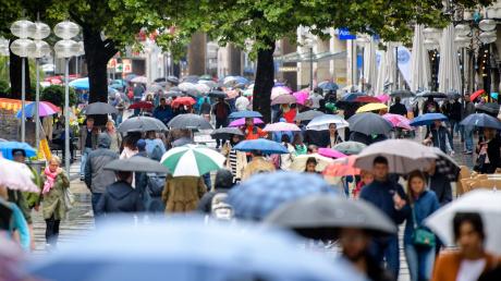 Passanten mit Regenschirmen laufen im Regen durch die Fußgängerzone Neuhauser Straße und Kaufingerstraße nahe dem Stachus in München.