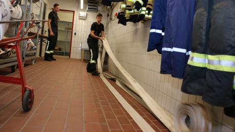 Aufräumarbeiten nach dem Hochwasser-Einsatz: Daniel Geiger (links) und Mario Rietzler von der Friedberger Feuerwehr rollen die benutzten Schläuche aus.