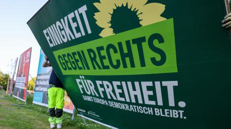 Zwei Mitarbeiter einer Firma für Werbeaufsteller bauen ein Wahlplakat der Partei „Bündnis 90/Die Grünen“ nach der Europawahl ab.