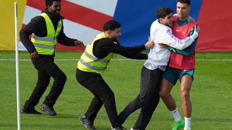 Ein Fan sprintet in Gütersloh auf den Trainingsplatz und umarmt Portugals Superstar Cristiano Ronaldo.