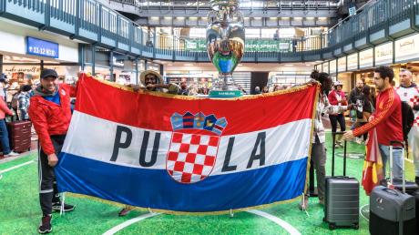 Kroatische Fußballfans posieren im Hamburger Hauptbahnhof mit ihrer Fahne.