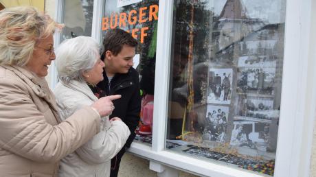 Johanna Wiesheu (links) und ihre Schwester Ingeborg Thaler erklären Daniel Wiesheu, wer auf den Faschingsfotos im Bürgertreff-Schaufenster in Utting zu sehen ist.