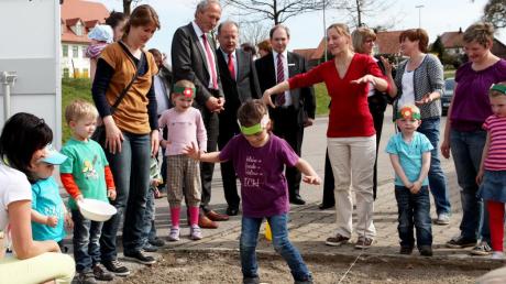 Mit Brettern an den Füßen drückten die Kindergartenkinder die Samen in die Erde. Landrat Hans-Joachim Weirather (Mitte) und rechts neben ihm Thomas Munding, Vorstandsvorsitzender der Sparkasse Memmingen-Lindau-Mindelheim, schauen aufmerksam zu. 