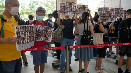 Unterstützer halten vor einem Gericht in Hongkong Plakate mit den Fotos einiger der 47 angeklagten Demokratie-Aktivisten in die Höhe.