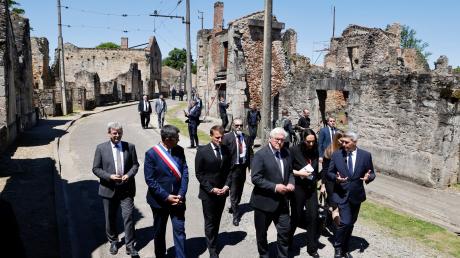 Der französische Präsident Emmanuel Macron und der deutsche Bundespräsident Frank-Walter Steinmeier gehen an Ruinen in Oradour-sur-Glane vorbei.